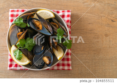 Mussels with herbs in a bowl with lemon 104855511