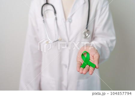 Doctor with green Ribbon for world Mental Health Day, Liver, Gallbladders, bile duct, cervical, kidney Cancer and Lymphoma Awareness month. Healthcare and world cancer day concept 104857794