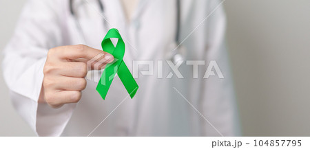 Doctor with green Ribbon for world Mental Health Day, Liver, Gallbladders, bile duct, cervical, kidney Cancer and Lymphoma Awareness month. Healthcare and world cancer day concept 104857795