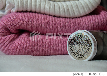 Anti-pilling razor. Device for shaving clothes. Anti-Plush fabric Shaver. Electric portable sweater pill defuzzer Lint remover from pink acrylic or wool sweater. Electric device fabric shaver after 104858188