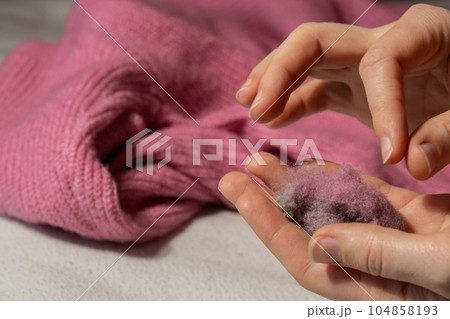 Woman using Anti-pilling razor at home. Device for shaving clothes. Anti-Plush fabric Shaver. Electric portable sweater pill defuzzer Lint remover from pink acrylic or wool sweater. Slow fashion Woman using Anti-pilling razor at home. Device for shaving clothes. Anti-Plush fabric Shaver. Electric portable sweater pill defuzzer Lint remover from pink acrylic or wool sweater. Slow fashion 104858193
