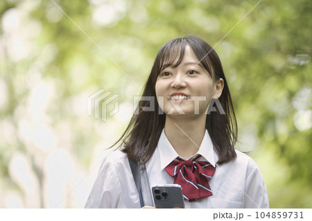新緑の中スマホを持つ女子高生 104859731