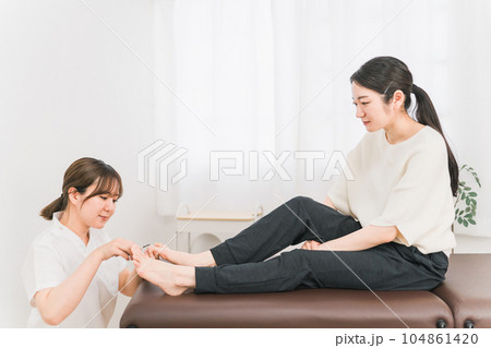 巻き爪・爪の治療をする白衣の女性と患者 巻き爪・爪の治療をする白衣の女性と患者 104861420