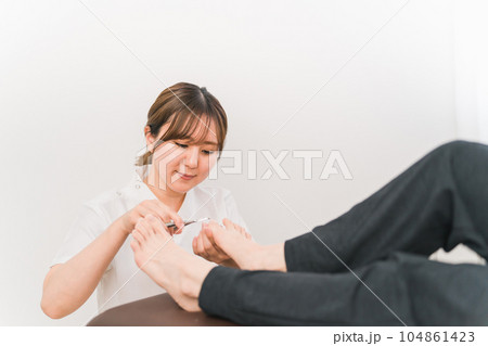 巻き爪・爪の治療をする白衣の女性と患者 巻き爪・爪の治療をする白衣の女性と患者 104861423