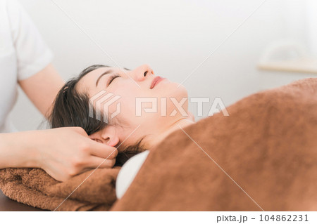 耳ツボマッサージの施術を受けるアジア人女性 耳ツボマッサージの施術を受けるアジア人女性 104862231