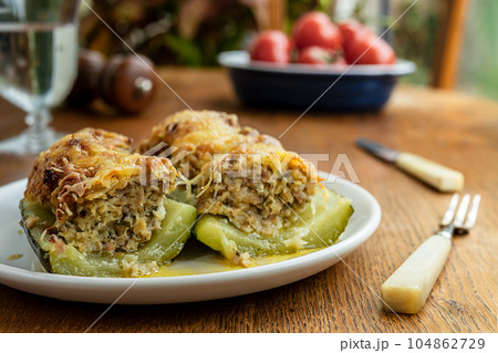 Stuffed zucchini, baked with meat, onions, herbs and cheese on the wooden table Stuffed zucchini, baked with meat, onions, herbs and cheese on the wooden table 104862729
