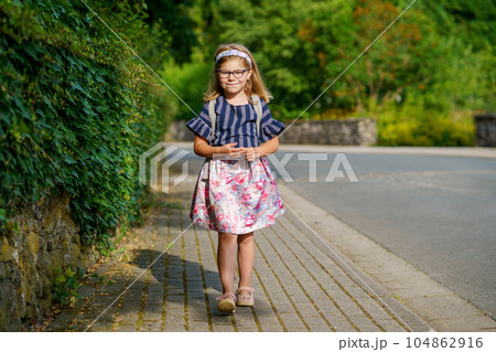 Little Preschool Girl on the Way to School. Healthy Happy Child Walking to Nursery School and Kindergarten. Smiling Child with Eyeglasses and Backpack on the City Street, Outdoors. Back to School. 104862916