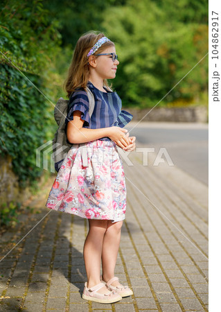 Little Preschool Girl on the Way to School. Healthy Happy Child Walking to Nursery School and Kindergarten. Smiling Child with Eyeglasses and Backpack on the City Street, Outdoors. Back to School. Little Preschool Girl on the Way to School. Healthy Happy Child Walking to Nursery School and Kindergarten. Smiling Child with Eyeglasses and Backpack on the City Street, Outdoors. Back to School. 104862917