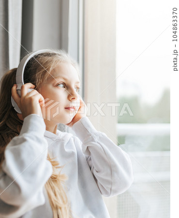 Little girl with headphones indoors at home 104863370