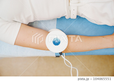 A patient on a magnetotherapy procedure on hand. 104865551