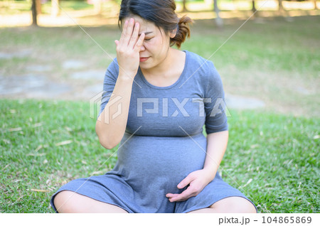 Pregnancy woman having headache and dizziness while her sitting in the park. Dizziness is one of the most common pregnancy symptoms, caused because your growing uterus puts pressure on blood vessels. Pregnancy woman having headache and dizziness while her sitting in the park. Dizziness is one of the most common pregnancy symptoms, caused because your growing uterus puts pressure on blood vessels. 104865869