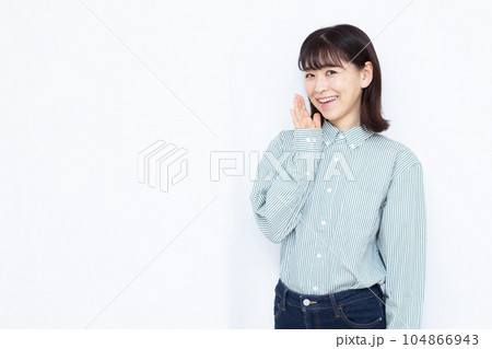 白い背景の前で笑顔でささやく30代の女性 白い背景の前で笑顔でささやく30代の女性 104866943