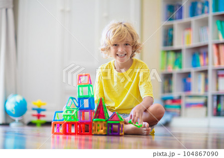 Child playing with magnetic building blocks. 104867090