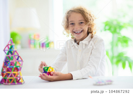 Child playing with magnetic building blocks. 104867292