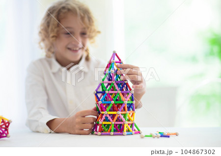 Child playing with magnetic building blocks. 104867302