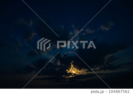 Moon in the clouds in the night sky 104867562