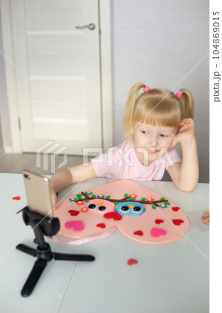 A blogger girl makes a felt craft for Valentine's Day in the shape of a heart. The concept of children's creativity and handmade. 104869015