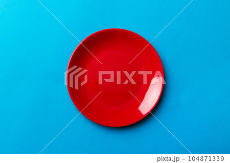 Top view of isolated of colored background empty round red plate for food. Empty dish with space for your design Top view of isolated of colored background empty round red plate for food. Empty dish with space for your design 104871339