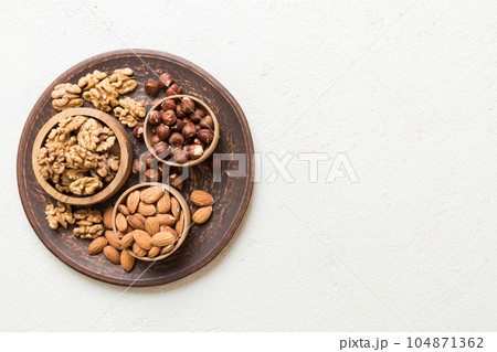 mixed nuts in wooden bowl. Mix of various nuts on colored background. pistachios, cashews, walnuts, hazelnuts, peanuts and brazil nuts 104871362