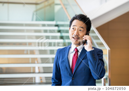 オフィスで電話するミドルのビジネスマン オフィスで電話するミドルのビジネスマン 104872050