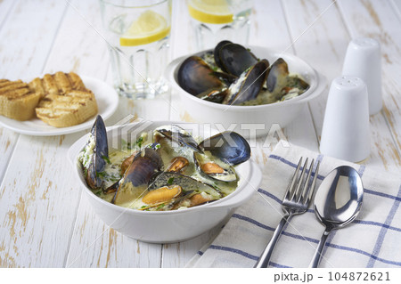 Bowl of seafood chowder with mussels and shrimp on a white table. 104872621