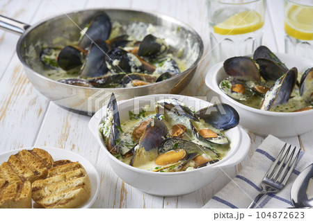 Traditional dish seafood chowder with slices of baguette on a white table. 104872623