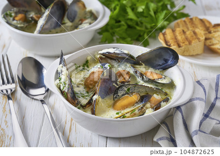 Delicious mediterranean seafood soup with mussels and prawns on a white table. 104872625