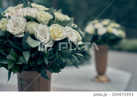 There are white roses in garden pots, on a blurry background. Flower arrangement, bouquet of garden flowers. It can be used for invitations, greetings, wedding cards. High quality photo There are white roses in garden pots, on a blurry background. Flower arrangement, bouquet of garden flowers. It can be used for invitations, greetings, wedding cards. High quality photo 104872933