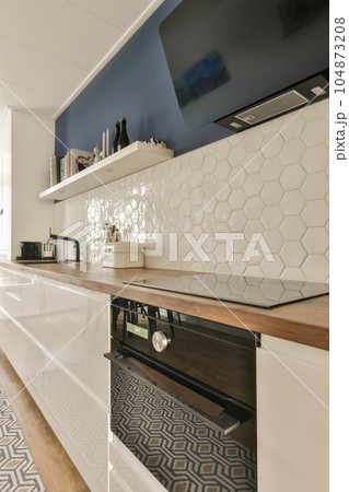 a modern kitchen with hexagon tiles on the backs and wood countertops in white, blue and black 104873208
