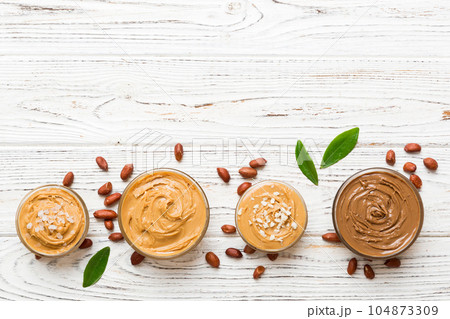 Glass jar with peanut butter on table background, top view space for text and close up Glass jar with peanut butter on table background, top view space for text and close up 104873309