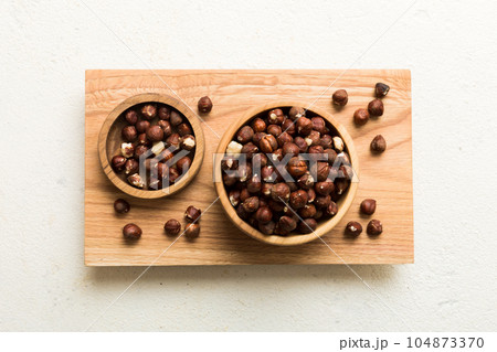 Wooden bowl full of hazelnuts on table background. Healthy eating concept. Super foods Wooden bowl full of hazelnuts on table background. Healthy eating concept. Super foods 104873370