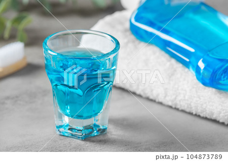 Mouthwash in glass cup on grey background, oral care Mouthwash in glass cup on grey background, oral care 104873789