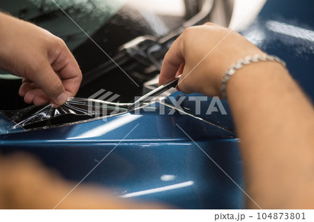 The master in the car service cuts the protective cutter.  104873801