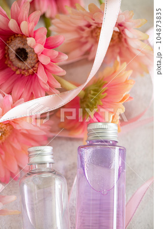 化粧品の入ったコスメボトルとお花とリボン 化粧品の入ったコスメボトルとお花とリボン 104873835