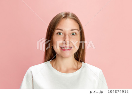 Portrait of young beautiful woman wearing white t-shirt, posing, looking at camera and cheerfully smiling against pink studio background 104874912