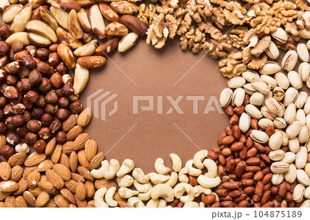 different nuts frame background. Close up, top view, flat lay with vopy space. Walnut, pistachios, almonds, hazelnuts and cashews 104875189