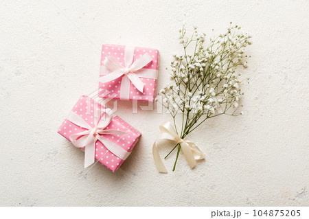 Gift or present box and flower gypsophila on light table top view. Greeting card. Flat lay style with copy space 104875205
