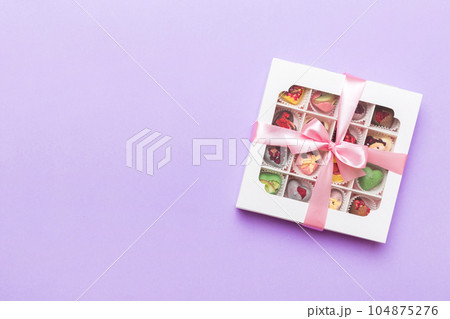 Box with sweet chocolate candies on color background, Various candy sweets. Valentines day gift box. Top view flat lay with copy space Box with sweet chocolate candies on color background, Various candy sweets. Valentines day gift box. Top view flat lay with copy space 104875276