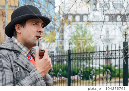 Portrait of a man smoking a pipe on a city street. 104876761