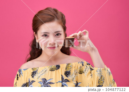 female model wearing a flower-patterned dress with a pink background and enjoying snacks female model wearing a flower-patterned dress with a pink background and enjoying snacks 104877122