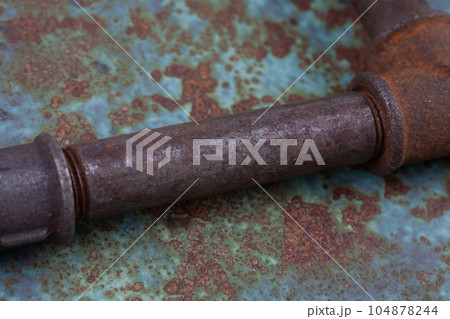 Rusty valve pipes on rusty metal wall 104878244