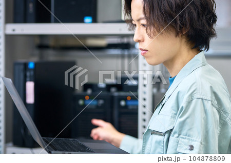 サーバを整備中のパソコンに向かうエンジニア サーバを整備中のパソコンに向かうエンジニア 104878809
