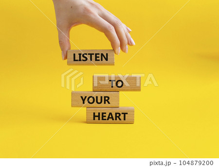 Listen to your heart symbol. Concept word Listen to your heart on wooden blocks. Beautiful yellow background. Businessman hand. Business and Listen to your heart concept. Copy space Listen to your heart symbol. Concept word Listen to your heart on wooden blocks. Beautiful yellow background. Businessman hand. Business and Listen to your heart concept. Copy space 104879200