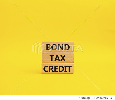 Bond Tax Credit symbol. Concept word Bond Tax Credit on wooden blocks. Beautiful yellow background. Business and Bond Tax Credit concept. Copy space 104879313