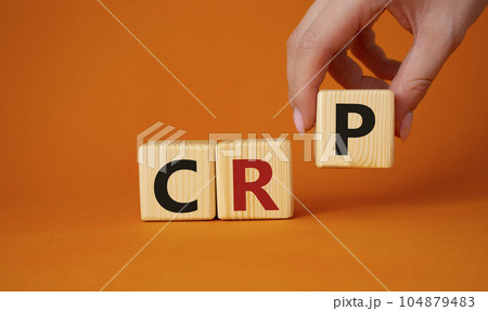 CRP - C-Reactive Protein Test symbol. Wooden cubes with word CRP. Doctor hand. Beautiful orange background. Medical and C-Reactive Protein Test concept. Copy space. 104879483
