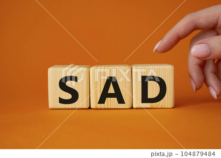 Sad symbol. Wooden cubes with words Sad. Businessman hand. Beautiful orange background. Business and Sad concept. Copy space. 104879484