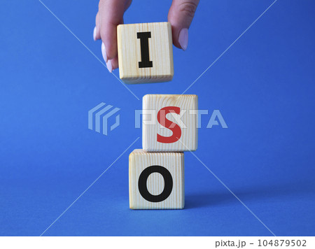 ISO standards quality control symbol. Concept word ISO on wooden cubes. Businessman hand. Beautiful blue background. Business and ISO concept. Copy space. ISO standards quality control symbol. Concept word ISO on wooden cubes. Businessman hand. Beautiful blue background. Business and ISO concept. Copy space. 104879502