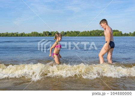 Children play in the water jumping on the waves. Summer holidays Children play in the water jumping on the waves. Summer holidays 104880000