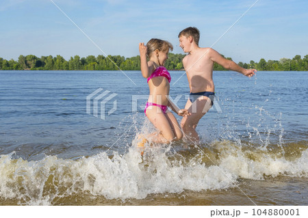 Children play in the water jumping on the waves. Children's vacation Children play in the water jumping on the waves. Children's vacation 104880001