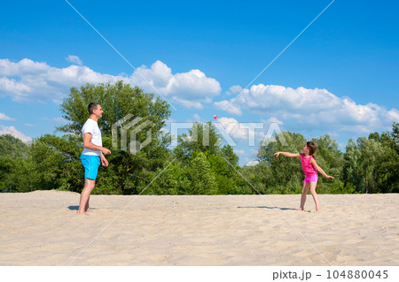 Family sports games on the beach. Father and daughter play badminton. Family sports games on the beach. Father and daughter play badminton. 104880045